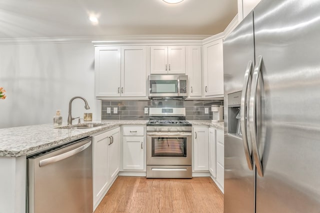 kitchen with appliances with stainless steel finishes, kitchen peninsula, and white cabinets