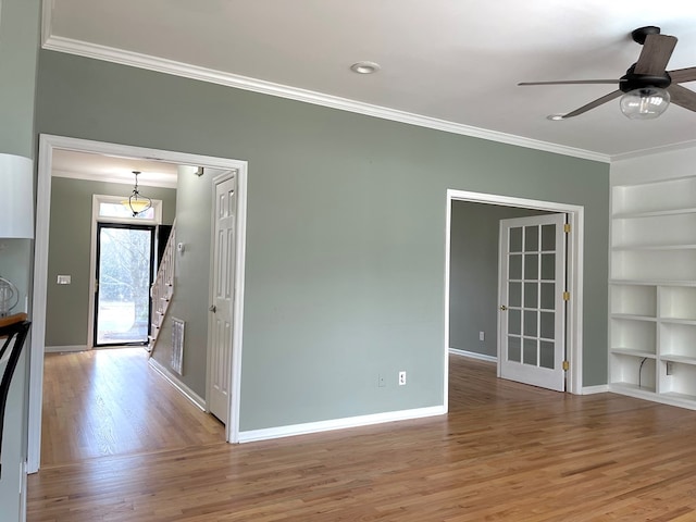 interior space with ornamental molding, ceiling fan, built in features, and light wood-type flooring