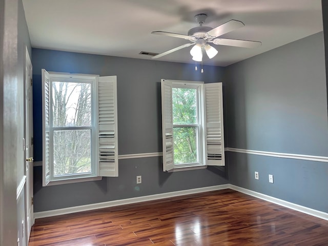 empty room featuring ceiling fan, a healthy amount of sunlight, and dark hardwood / wood-style flooring