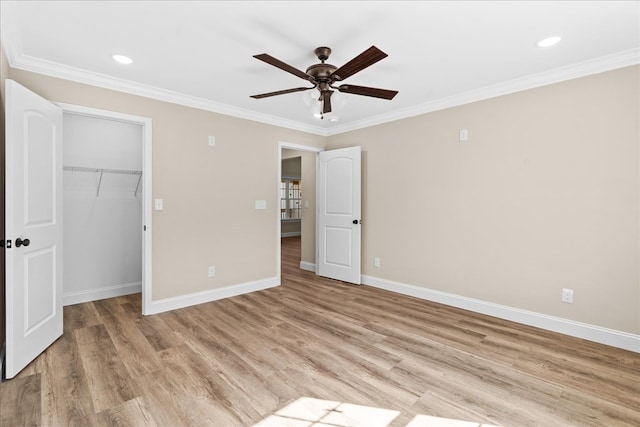 unfurnished bedroom with a closet, a walk in closet, light wood-style floors, baseboards, and ornamental molding