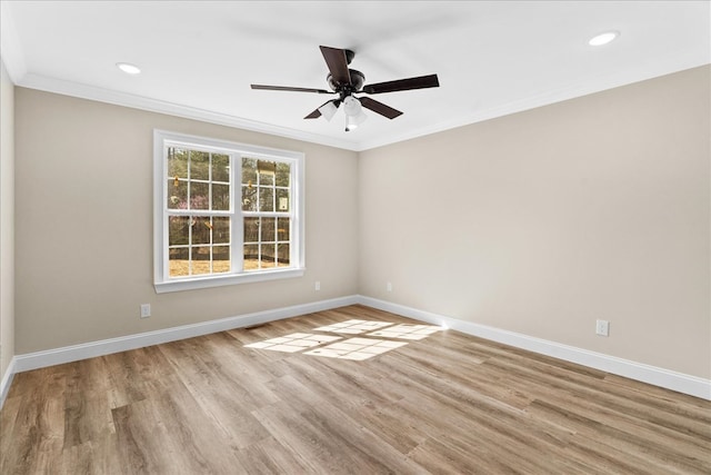 spare room with wood finished floors, a ceiling fan, baseboards, and ornamental molding