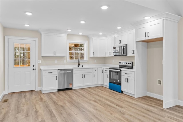 kitchen with baseboards, appliances with stainless steel finishes, a sink, and light wood finished floors