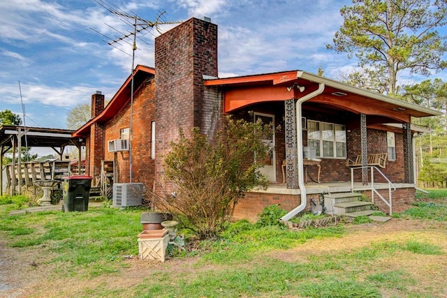 back of house with a yard, central air condition unit, and covered porch