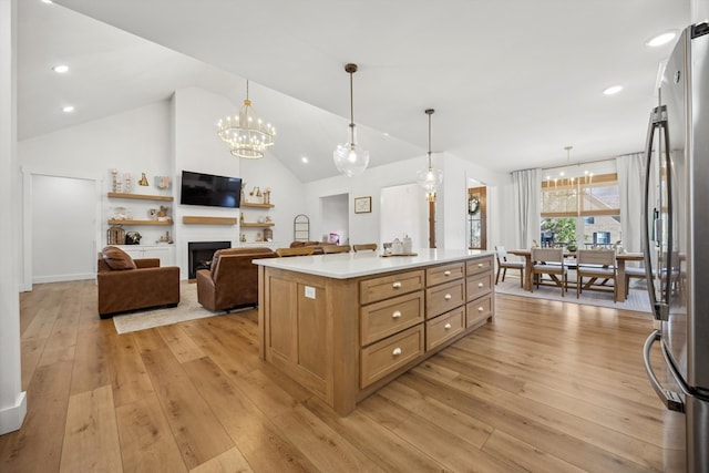 kitchen featuring decorative light fixtures, light countertops, freestanding refrigerator, light wood-style floors, and a notable chandelier