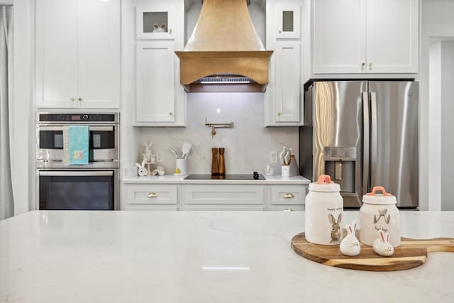 kitchen featuring stainless steel appliances, glass insert cabinets, custom exhaust hood, and white cabinets