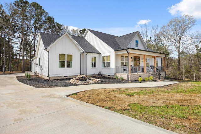 modern farmhouse featuring a porch, concrete driveway, board and batten siding, and crawl space