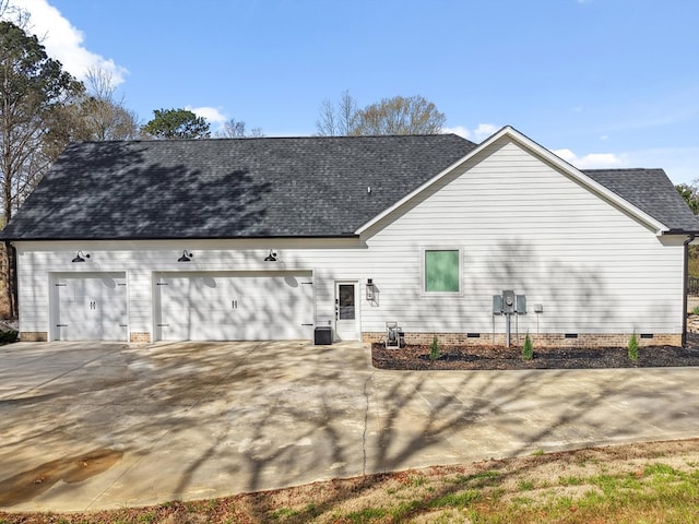 back of house with a shingled roof, concrete driveway, an attached garage, and crawl space