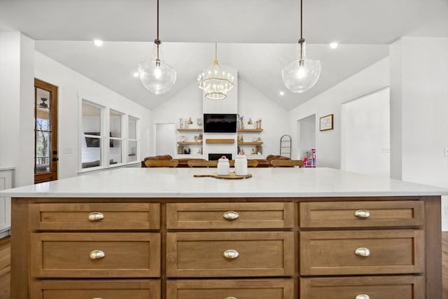 kitchen featuring vaulted ceiling, light stone counters, open floor plan, and pendant lighting