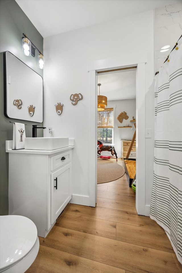 bathroom with curtained shower, baseboards, wood finished floors, and vanity