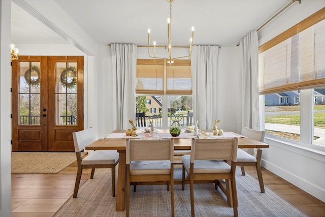 dining area with baseboards, an inviting chandelier, and wood finished floors
