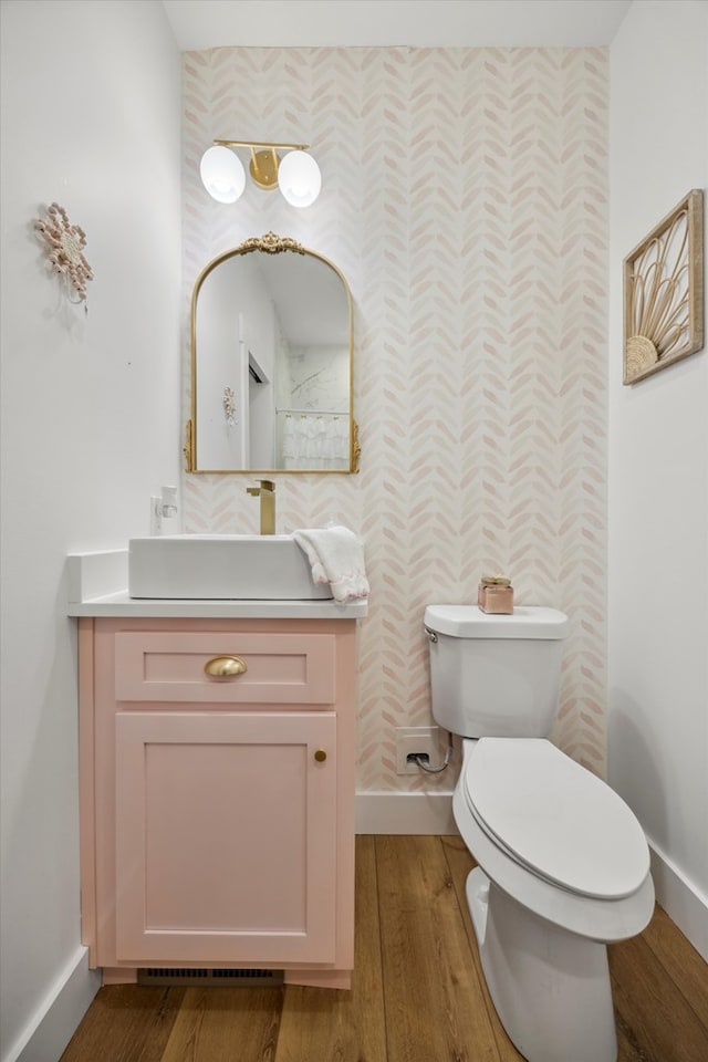 bathroom featuring baseboards, toilet, wood finished floors, and vanity