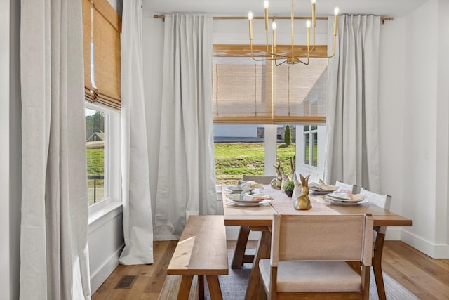 dining room with visible vents, baseboards, an inviting chandelier, and hardwood / wood-style flooring