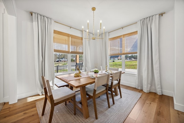 dining space featuring an inviting chandelier, light wood-style floors, and baseboards