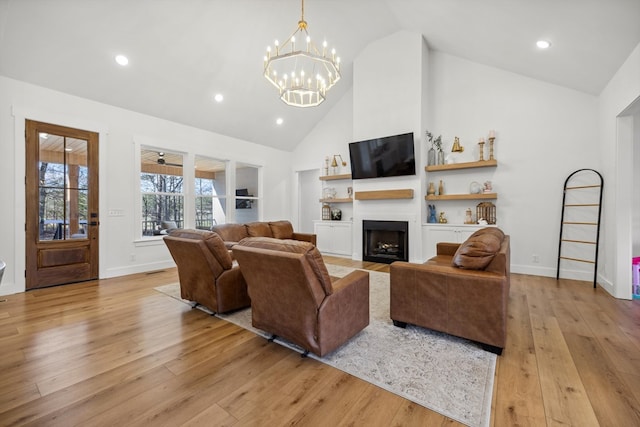 living area with a fireplace with flush hearth, high vaulted ceiling, and light wood-style flooring
