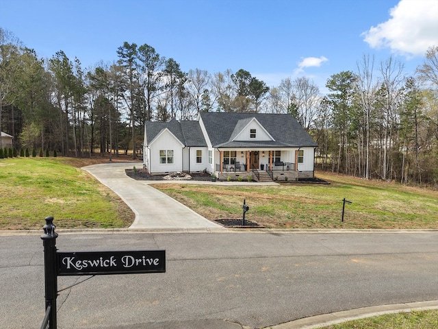 modern farmhouse with covered porch, concrete driveway, and a front yard