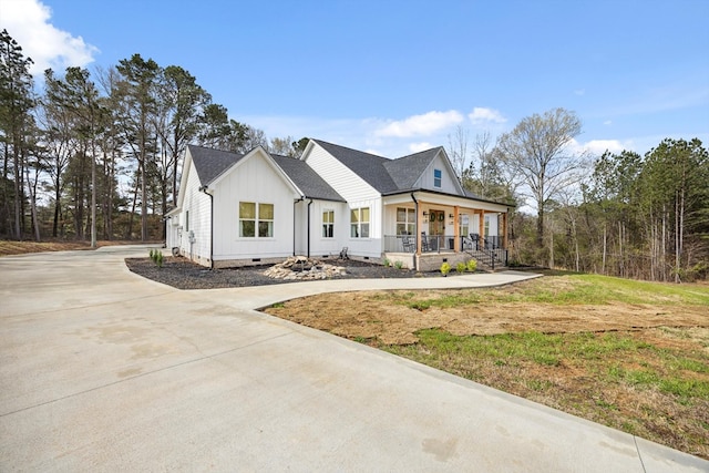 modern farmhouse with board and batten siding, a shingled roof, a porch, concrete driveway, and crawl space