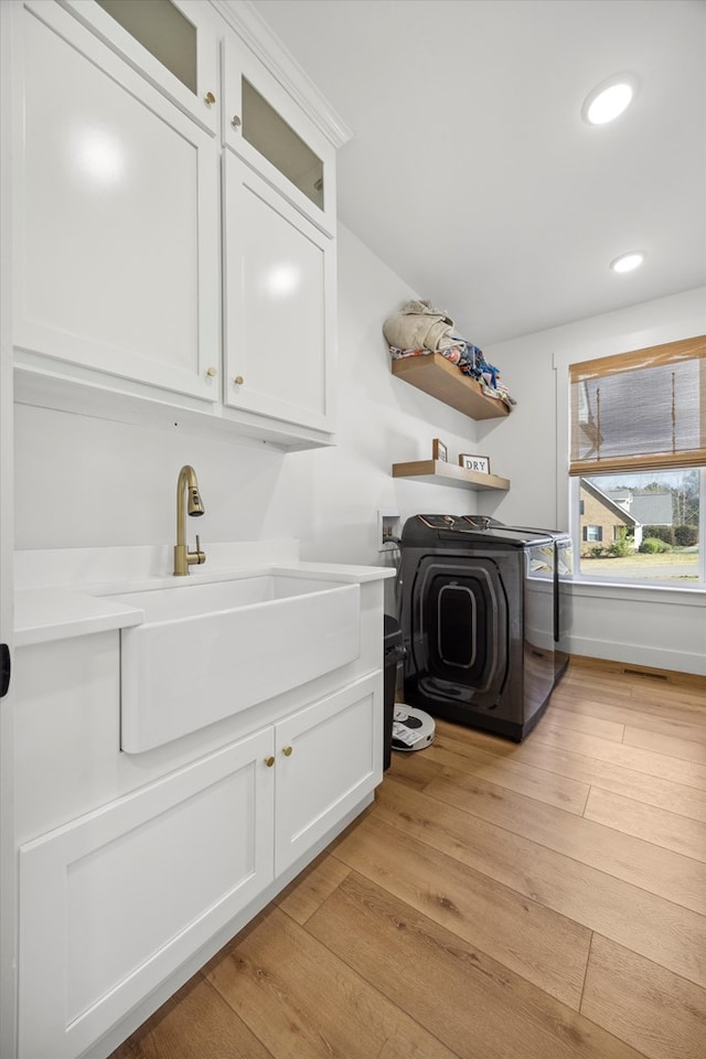 laundry room featuring light wood finished floors, washer / clothes dryer, cabinet space, recessed lighting, and a sink