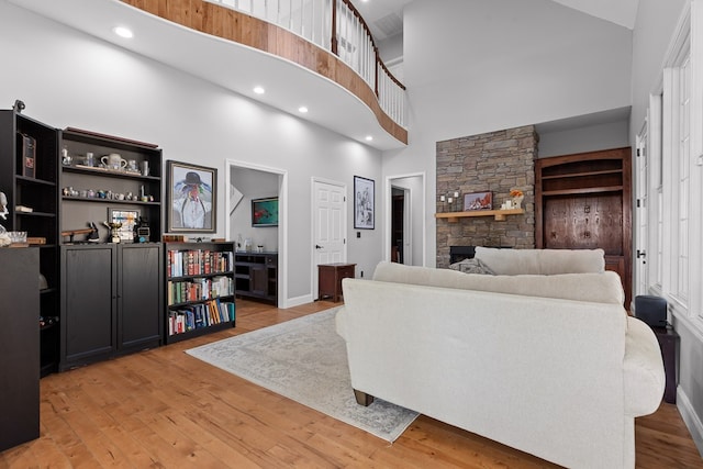 living room featuring a high ceiling, a fireplace, and light wood-type flooring