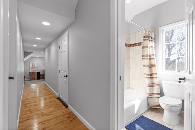 bathroom with shower / bathtub combination with curtain, wood-type flooring, and toilet