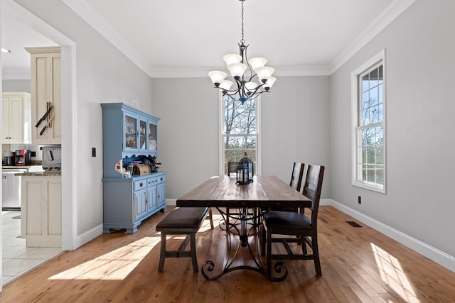 dining area with crown molding, light hardwood / wood-style flooring, and a chandelier