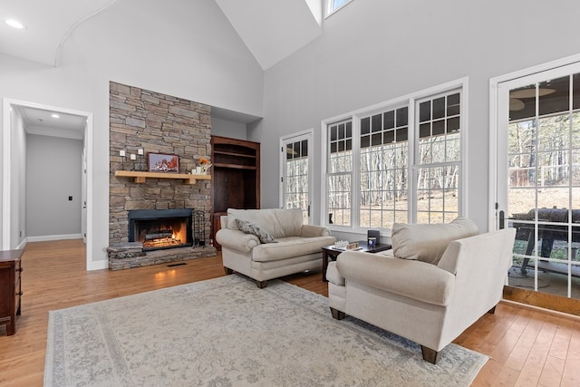 living room featuring hardwood / wood-style floors, a stone fireplace, and high vaulted ceiling