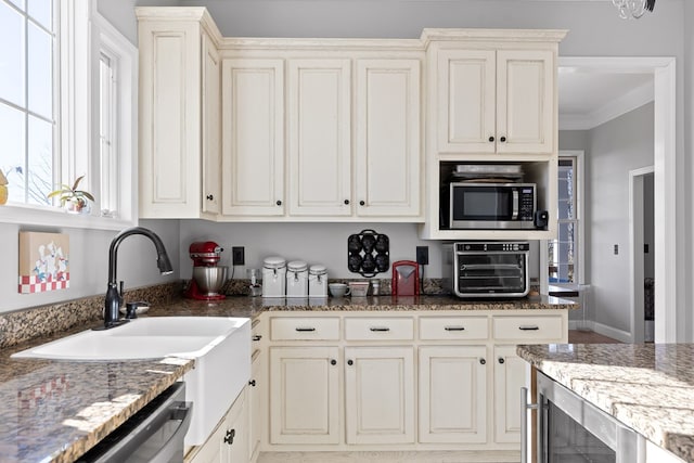 kitchen with cream cabinetry, stainless steel appliances, and dark stone countertops