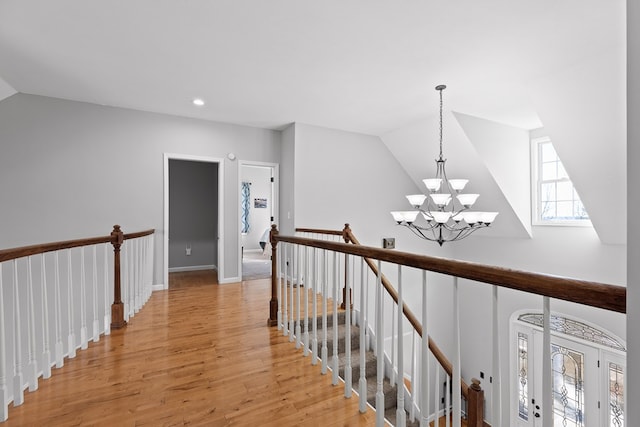 hallway featuring vaulted ceiling, light hardwood / wood-style flooring, and a notable chandelier