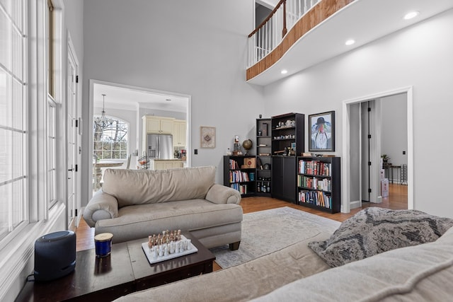 living room with a notable chandelier, light hardwood / wood-style flooring, and a high ceiling