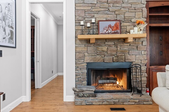 details with ornamental molding, a stone fireplace, and hardwood / wood-style floors