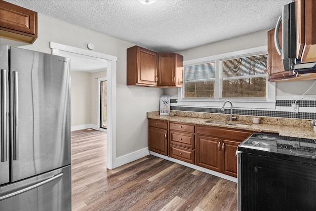 kitchen featuring dark hardwood / wood-style flooring, appliances with stainless steel finishes, sink, and light stone counters