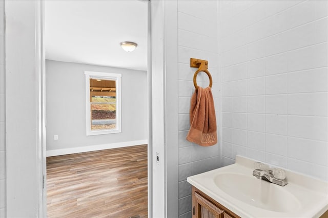 bathroom with wood-type flooring, tile walls, and vanity