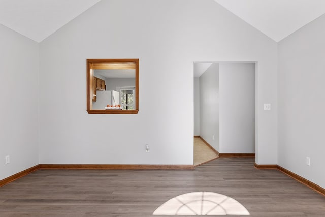 spare room featuring wood-type flooring and high vaulted ceiling