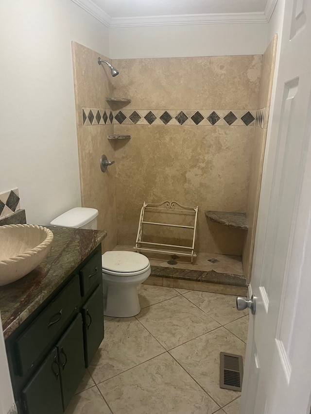 bathroom featuring crown molding, tile patterned flooring, a tile shower, vanity, and toilet