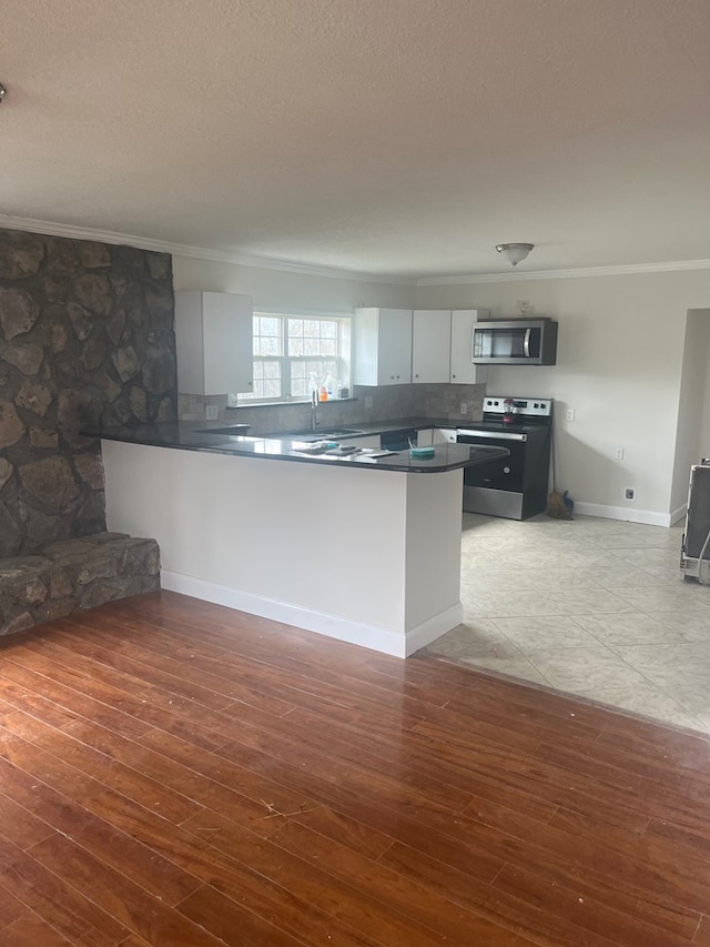 kitchen featuring stainless steel appliances, crown molding, white cabinets, and kitchen peninsula