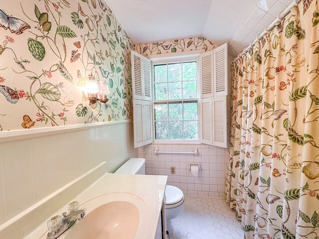 705 Greenwood Dr, Dalton, GA 30720 - bathroom with vanity, wainscoting, lofted ceiling, toilet, and wallpapered walls