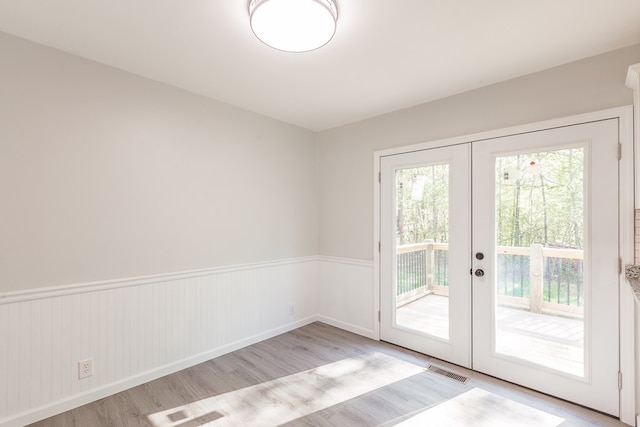 doorway to outside featuring a wainscoted wall, wood finished floors, french doors, and visible vents