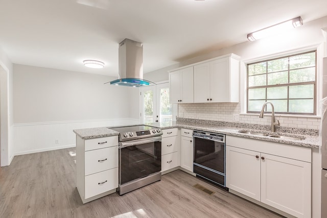 kitchen with black dishwasher, a peninsula, electric stove, island range hood, and a sink