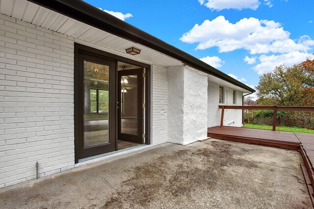 entrance to property featuring a wooden deck and a patio