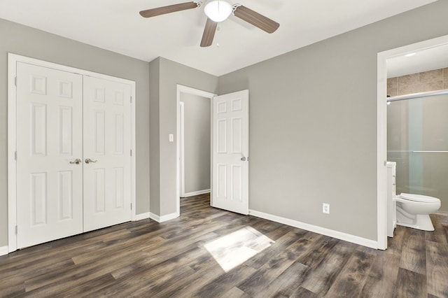 unfurnished bedroom featuring ensuite bathroom, dark wood-type flooring, ceiling fan, and a closet