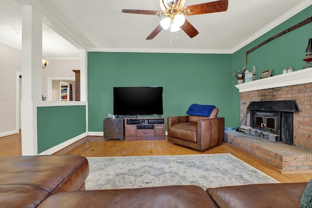 living room featuring crown molding, a brick fireplace, ceiling fan, and light hardwood / wood-style flooring