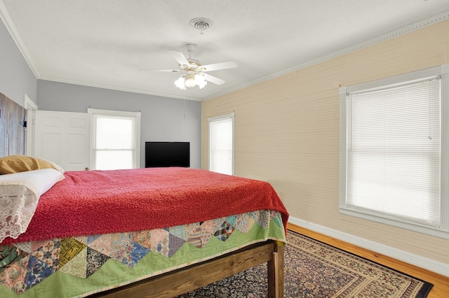 bedroom featuring ceiling fan, ornamental molding, wood-type flooring, and a textured ceiling