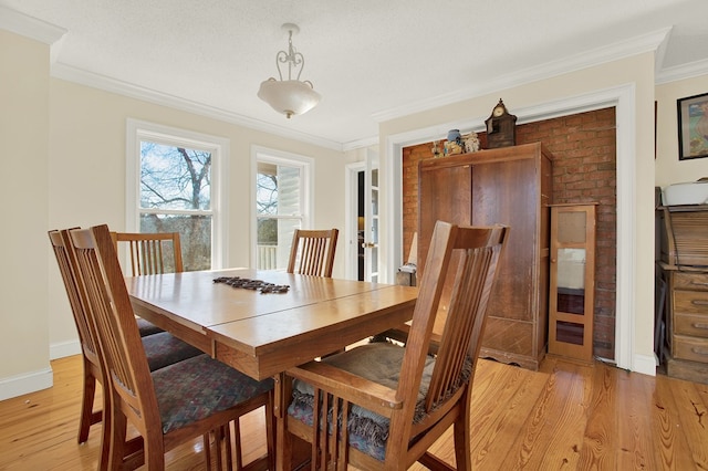 dining room featuring ornamental molding, light hardwood / wood-style flooring, and a textured ceiling