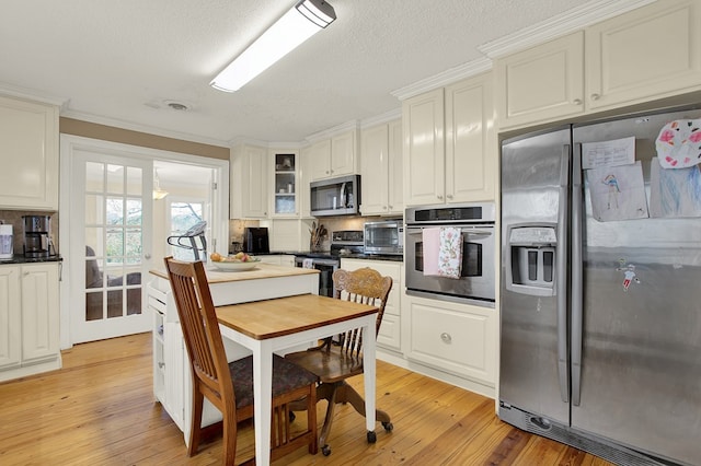 kitchen featuring stainless steel appliances, a textured ceiling, white cabinets, and light hardwood / wood-style floors