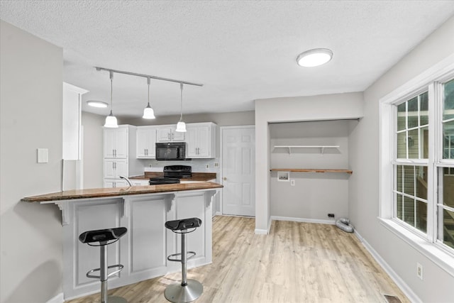 353 Diamond Way, Chatsworth, GA 30705 - kitchen with black appliances, a kitchen breakfast bar, light wood-style floors, and a textured ceiling