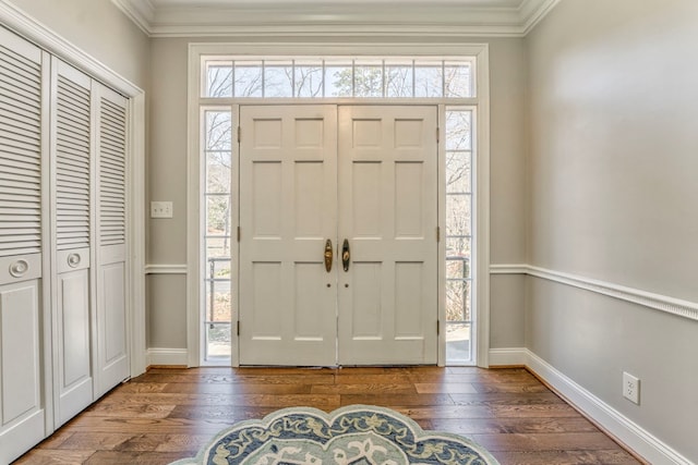 entryway with ornamental molding and dark hardwood / wood-style floors