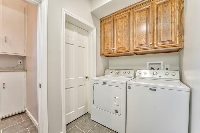 laundry area with separate washer and dryer, light tile patterned floors, and cabinets