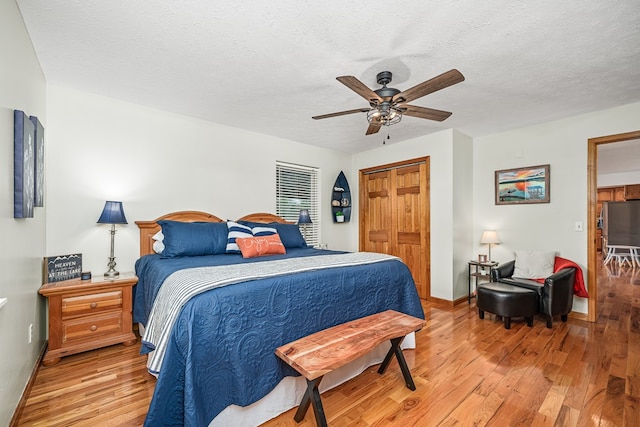 bedroom with a textured ceiling, light wood finished floors, and baseboards