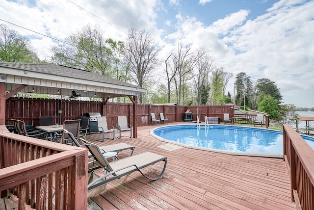 view of swimming pool with a wooden deck, fence, outdoor dining space, and a fenced in pool