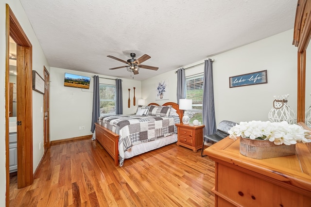 bedroom with ceiling fan, multiple windows, a textured ceiling, and light wood-style flooring