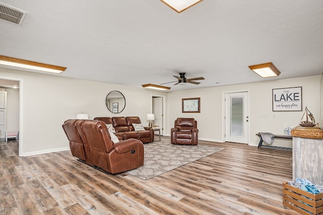 living area with ceiling fan, baseboards, wood finished floors, and visible vents